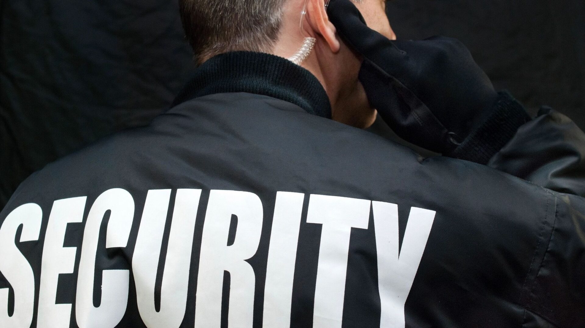 A man in black jacket holding his ear.
